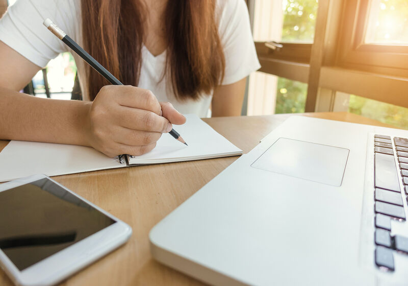 Woman working at computer with notebook
